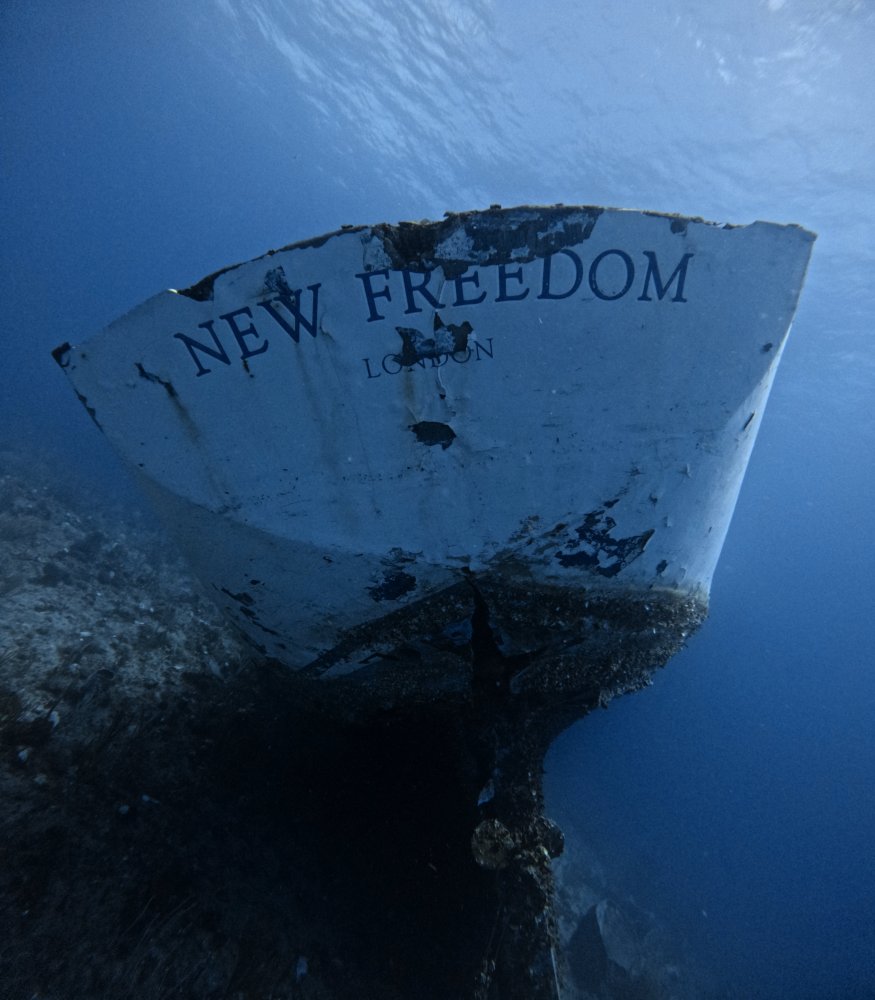 Underwater view of a partially submerged boat's stern with 'NEW FREEDOM LONDON' text.