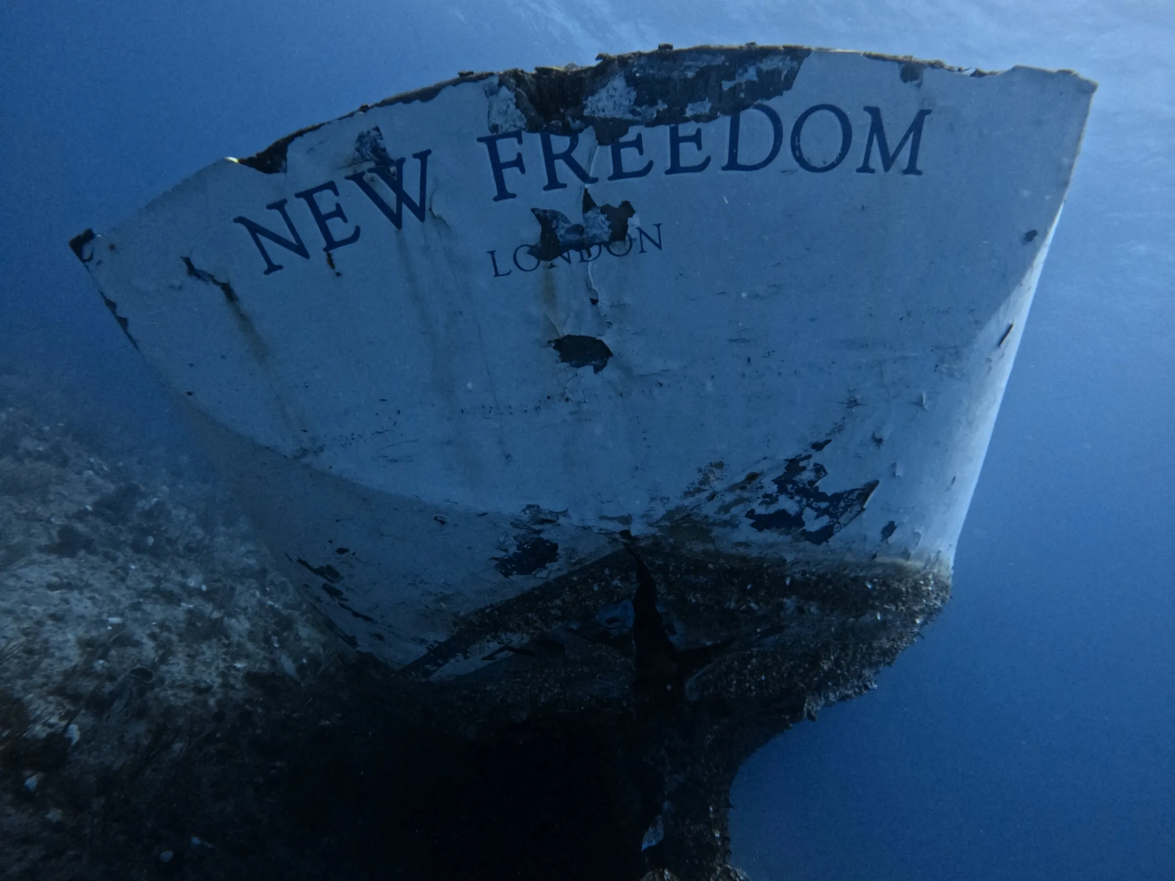 Underwater view of a partially submerged boat's stern with 'NEW FREEDOM LONDON' text.